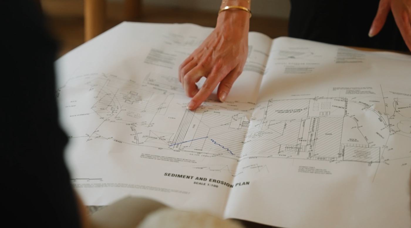 Hands reviewing detailed site plans and construction drawings on a table