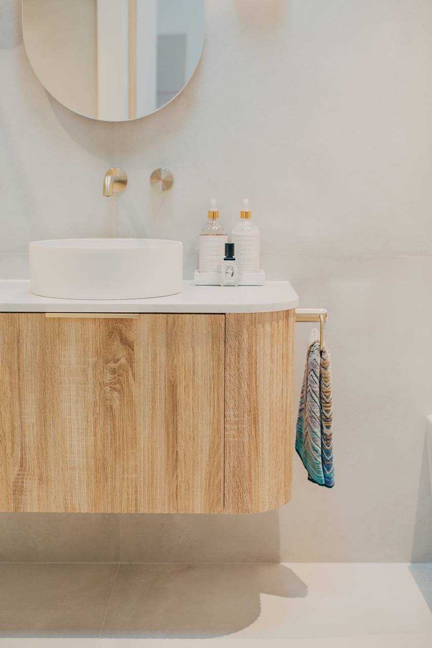 Bathroom with a timber vanity, vessel basin and brass tapware in the Castle Hill home