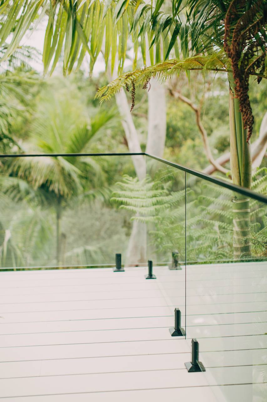 Elevated deck with a glass balustrade and a leafy, treehouse-like bushland outlook